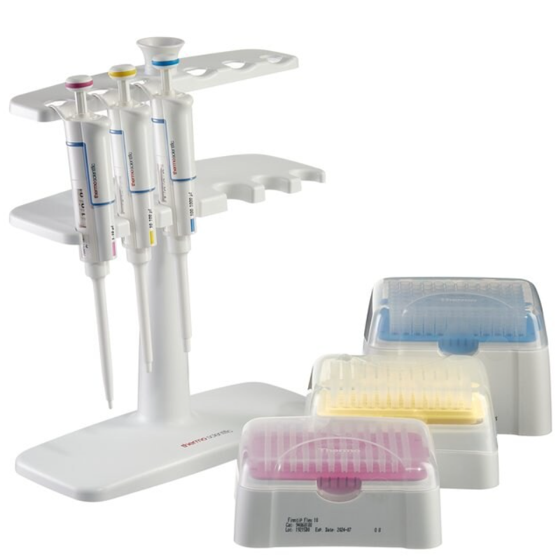 Three Thermo Scientific Finnpipette F1 single channel, variable volume pipettes (10μL, 100μL, 1000μL) from the GLP F1 Kit 1 are displayed on a stand beside three boxes of color-coded pipette tips with plastic lids.