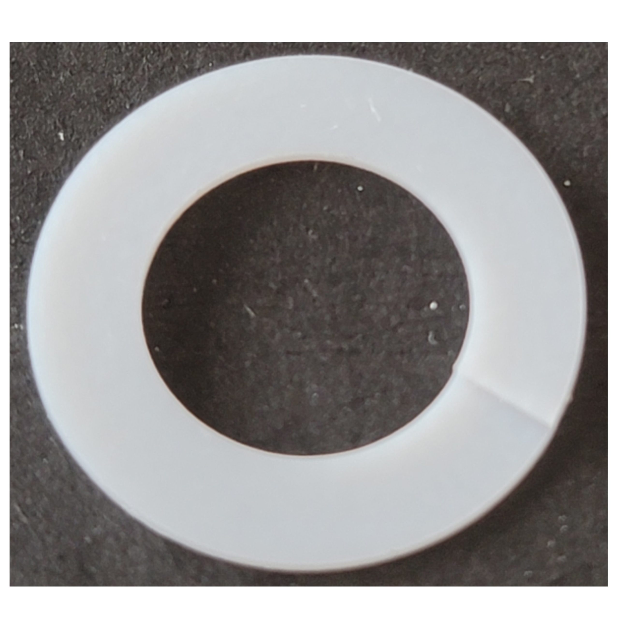 A Nichiryo / Oxford white circular plastic lock washer with a small cut, displayed on a dark background.