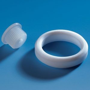 A Dispensette Membrane Filter Connector Assembly for Accessory Port (BrandTech), including a white plastic plug and matching circular ring, is displayed on a blue surface.