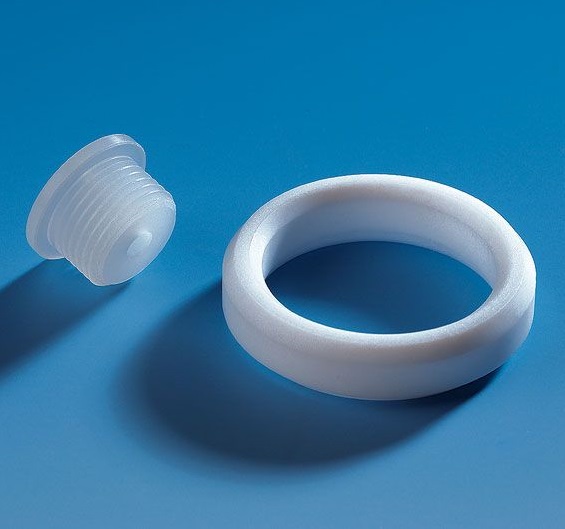 BT 704495_ A Dispensette Membrane Filter Connector Assembly for Accessory Port (BrandTech), including a white plastic plug and matching circular ring, is displayed on a blue surface.