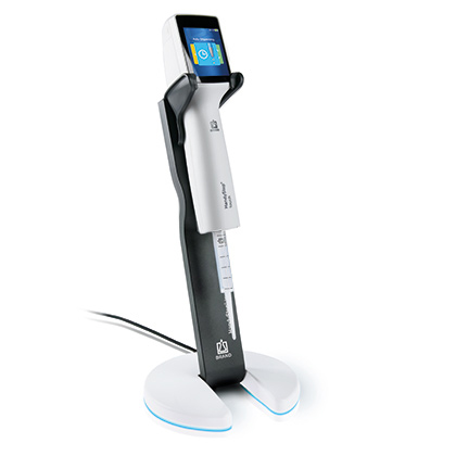 The HandyStep touch Electronic Repeating Pipette & Inductive Charging Stand Bundle (BrandTech) features a digital display and sits on a sleek charging stand with a power cord—perfect for seamless use in your lab.