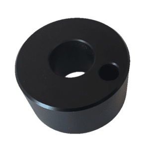 A black cylindrical metal Gilson Pipetman / Rainin Classic Platen for pipette supplies, featuring one large central hole and a smaller off-center hole on its flat surface.