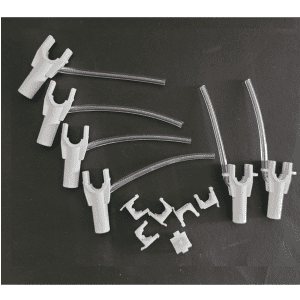 Six white connectors with clear tubes and six separate clips are arranged on black, resembling a Rainin Nozzle Set with Tubing, Adjustable Spacer Multichannel, 6 Channel, 1200μL.