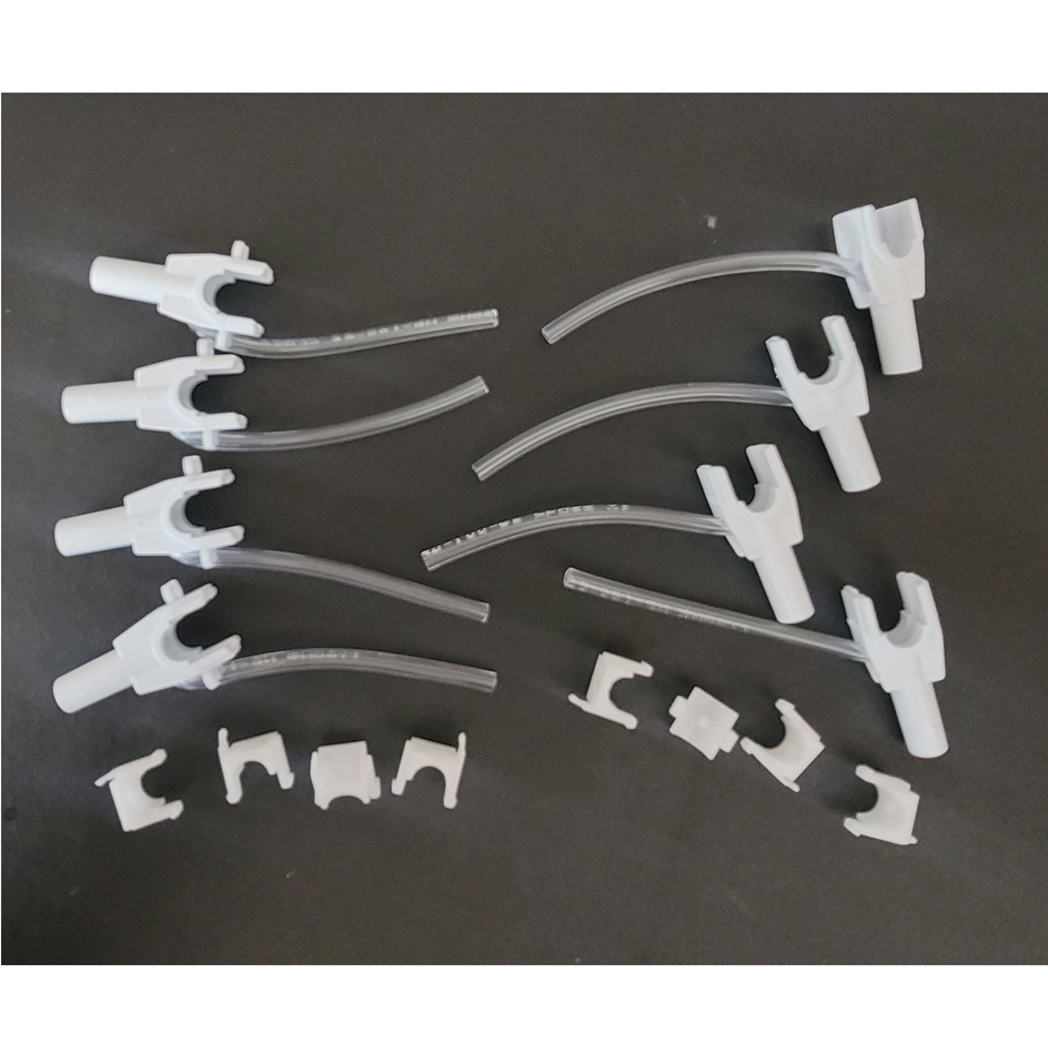 Several white plastic connectors and clips with clear tubing, resembling parts from the Rainin Nozzle Set with Tubing, Adjustable Spacer Multichannel, 8 Channel, 300μL (Rainin), are arranged on a black surface.
