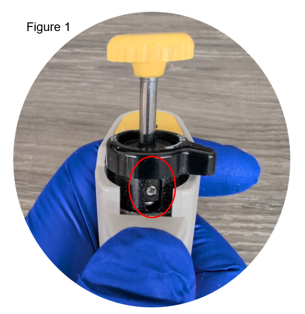A gloved hand holds a device with a yellow knob, featuring a highlighted silver screw near the top for precise nichiryo adjustment.