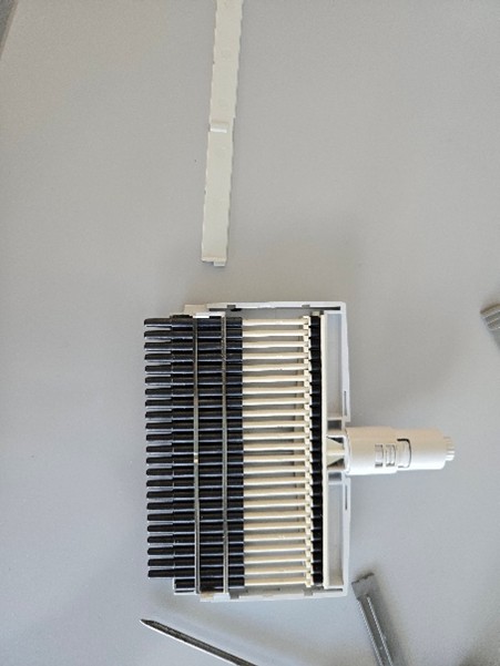 A close-up of a white and black Eppendorf Research Plus multichannel mechanical device with multiple pistons and nose cones, placed on a light surface.