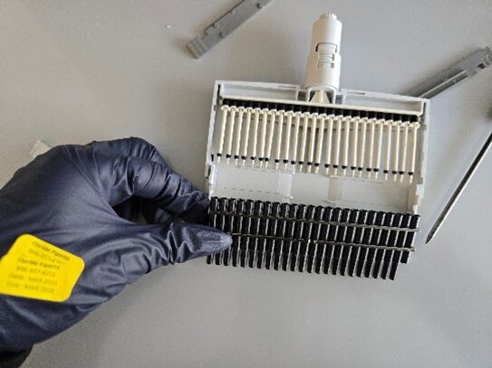 A gloved hand holds a nose cone assembly on a gray surface