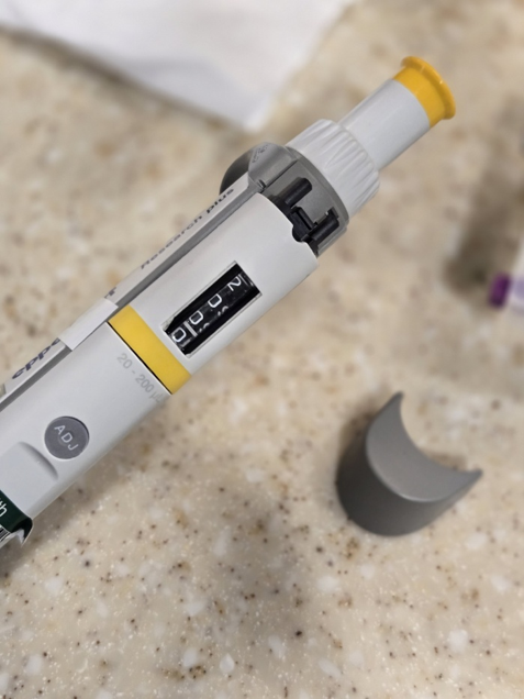 A close-up of a laboratory micropipette set to 200 microliters, lying on a speckled countertop with its ejector button removed.